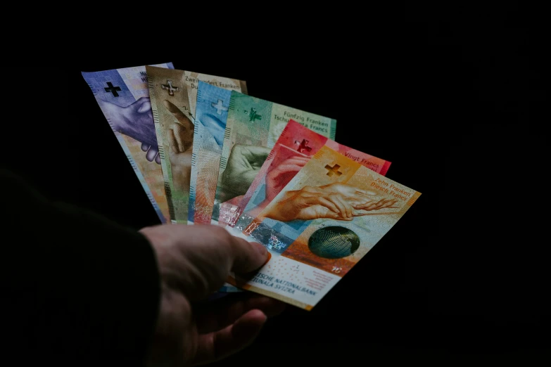 a person holding five different different colors notes