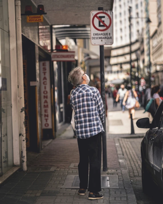 a man standing under a no parking sign next to a street
