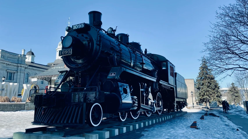 an unusual black train sitting in the middle of snowy pavement