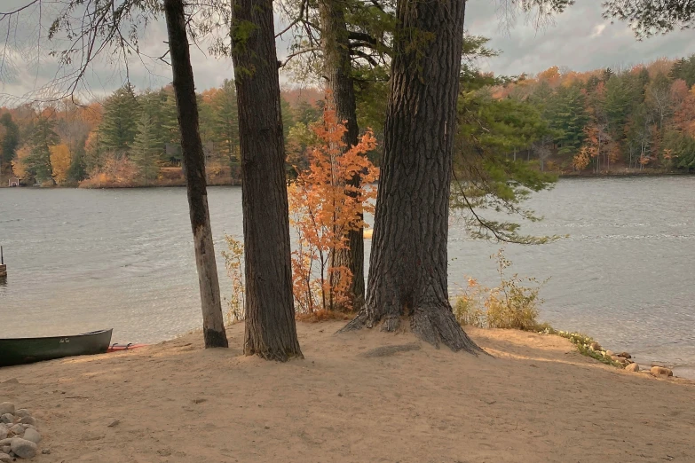 a canoe sits on the edge of the shore as a boat is in the water