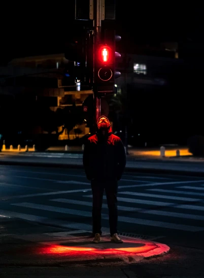 a man standing at the corner of a crosswalk at night