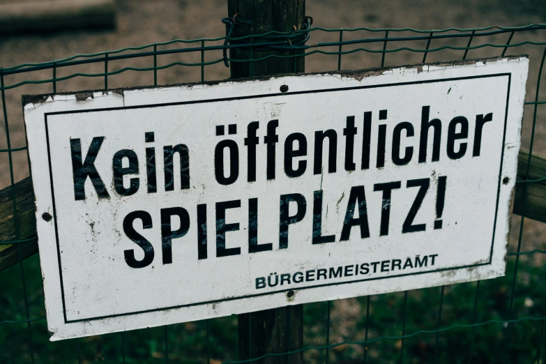 a sign posted on a fence that says,'kein differnticher spielplatz