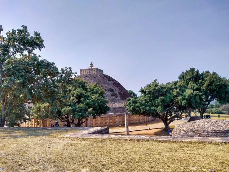 trees line the ground in front of the large stone structure