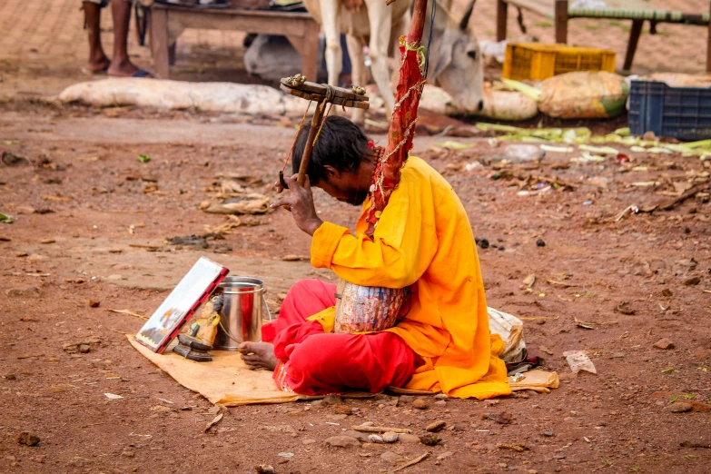 a man sitting in front of a cow painting a picture