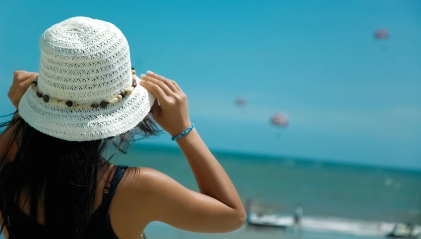 a woman wearing a hat on the beach