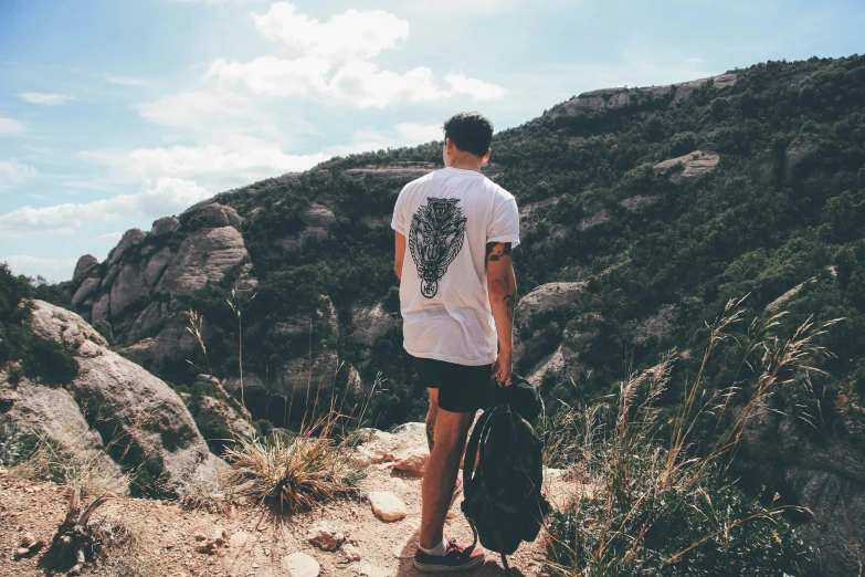 a man looking out at the mountains in the wild