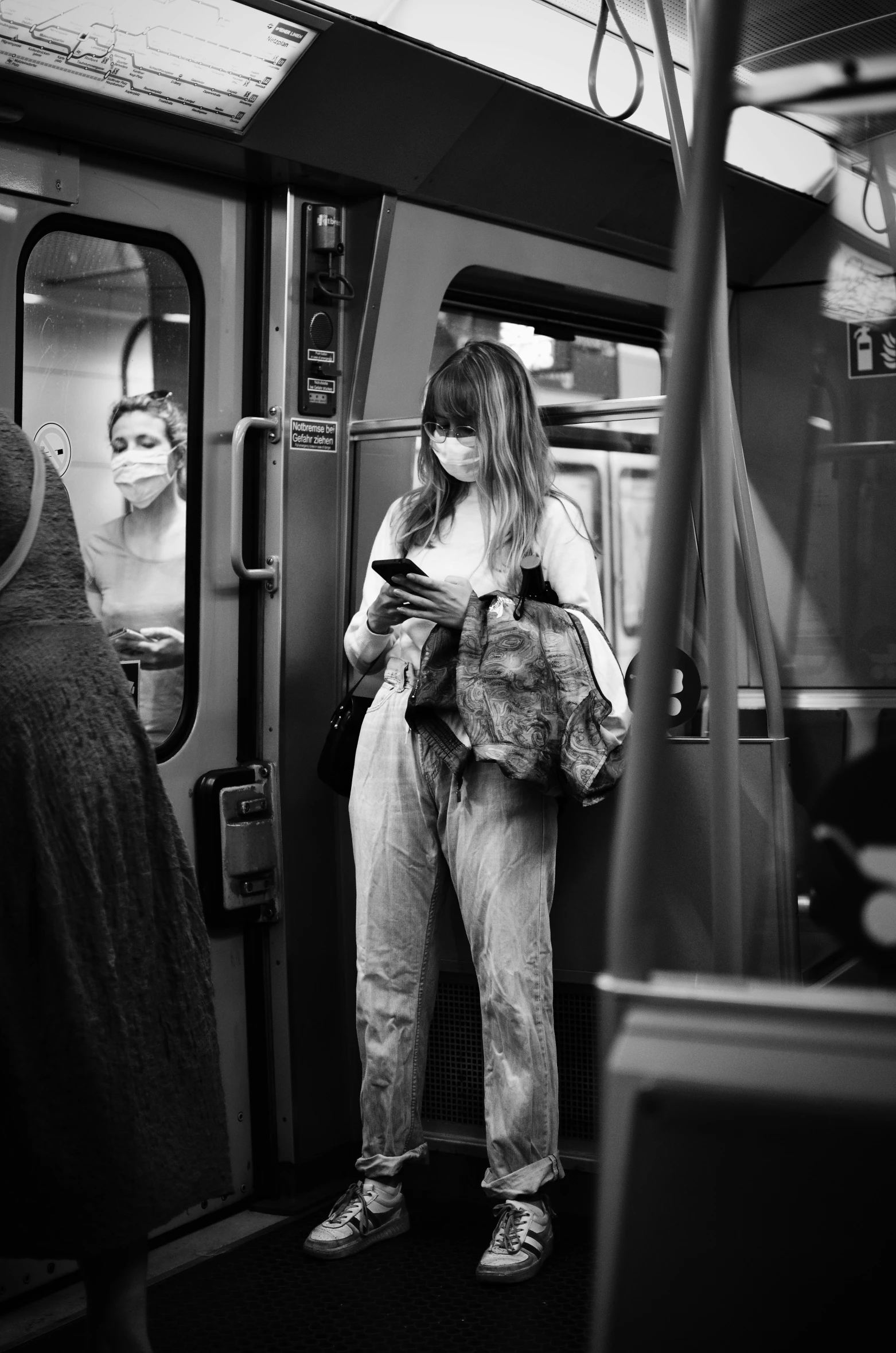 a woman standing on a subway looking at her phone