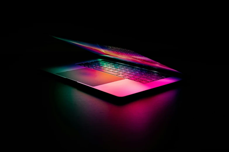 an apple laptop is sitting alone in the dark