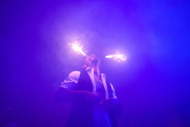 a man is standing in the smoke holding a lit sparkler