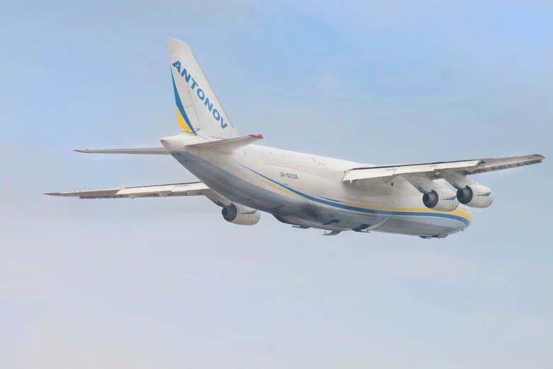 an airplane with a yellow stripe on its tail flying in the air