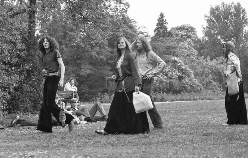 three women in long skirts are walking outside in the grass