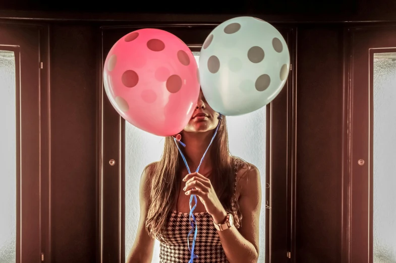 a woman holding balloons and string with polka dot designs