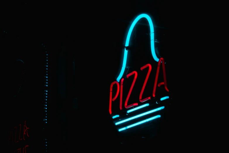 a neon sign in the shape of a slice of pizza on a street