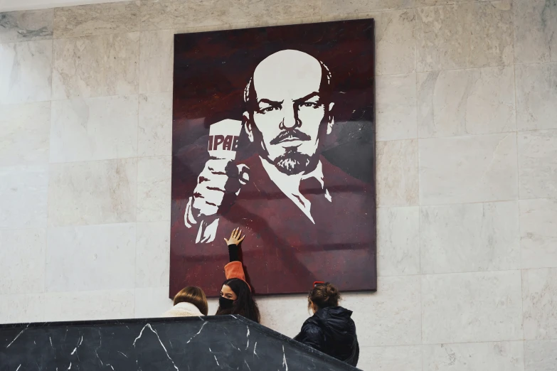 two people sitting on stairs near a poster with a painting of a man with a fist