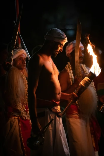 two people dressed up with long hair standing around in costume holding torches