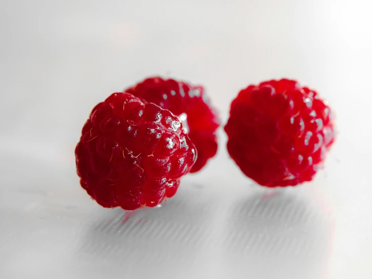 three berries with water on them are placed near each other