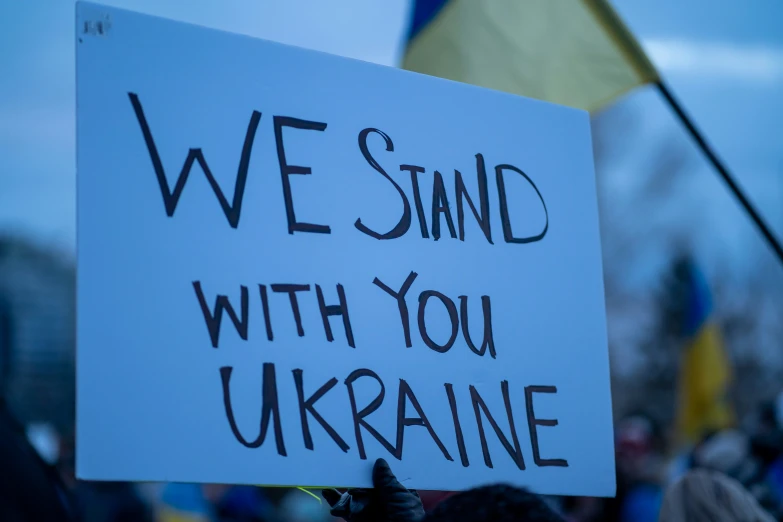 a white sign with words we stand with you ukraine