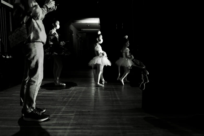 two women in dance dresses, and a man in an apron and a tie