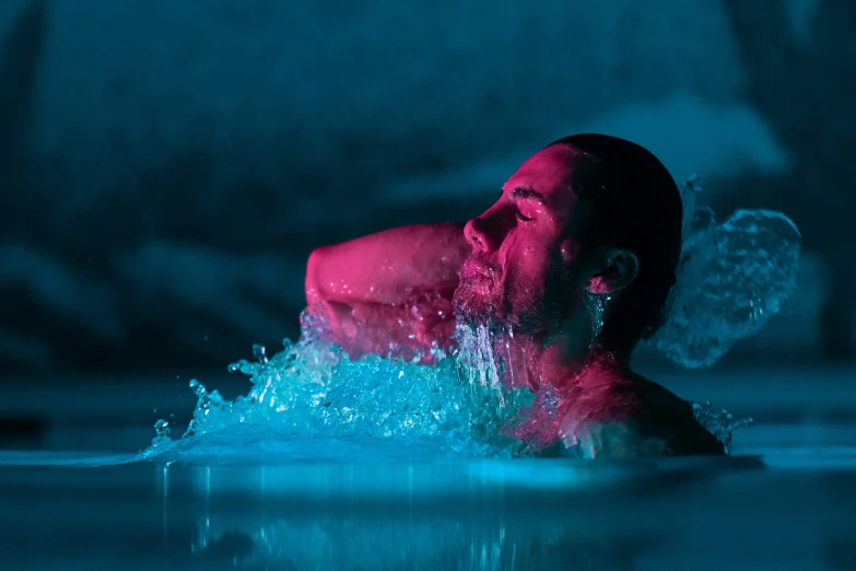 a man in a pool splashing water into his face