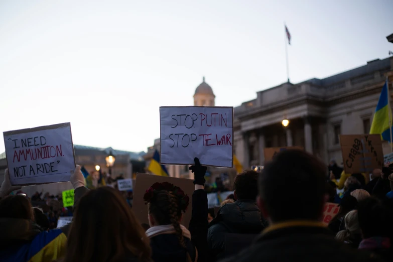 two people standing in front of a white building holding up signs