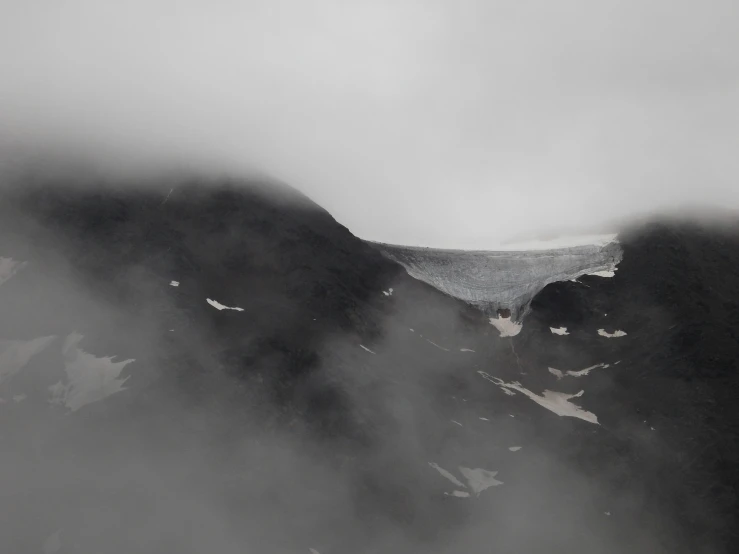 a mountain covered in fog in a black and white po