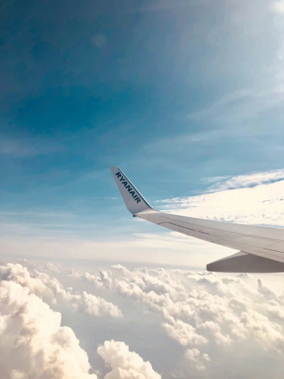 looking down at the wing of a jetliner while it is above the clouds