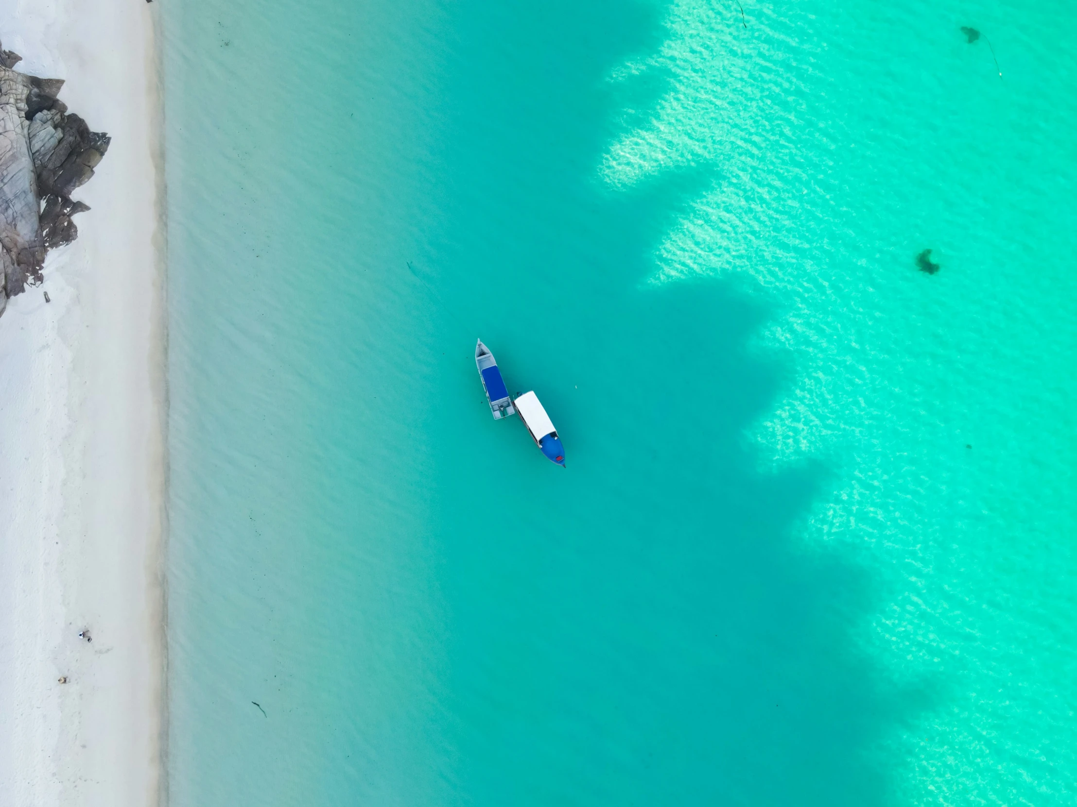 an aerial view of boats in the shallow water on a beach