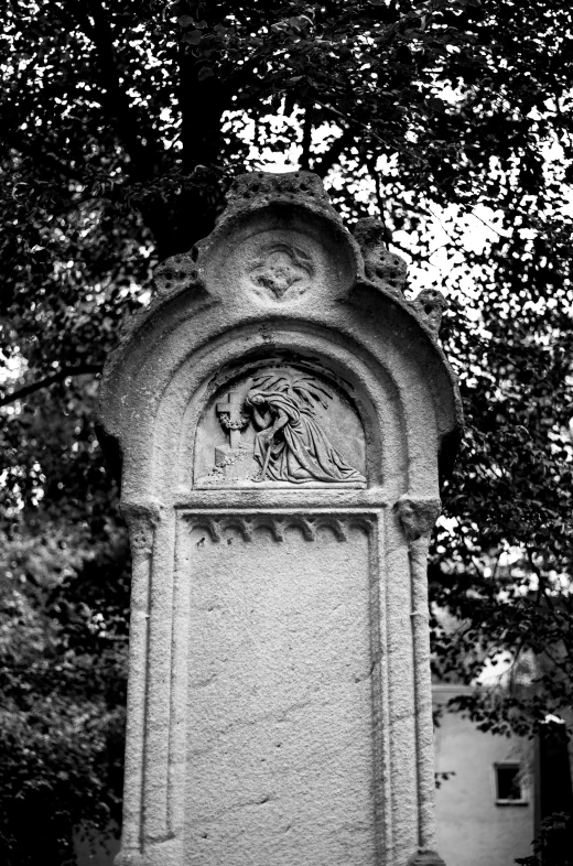 a tombstone with faces on it in the middle of a dark cemetery