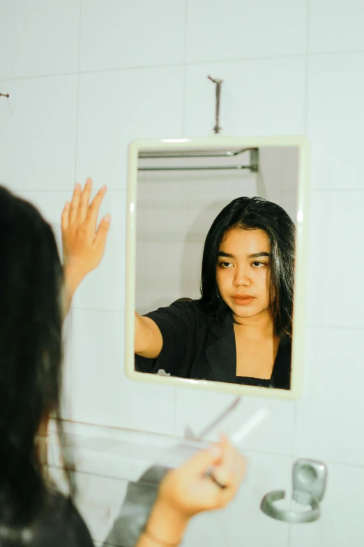 a woman holding her hands up in front of a mirror