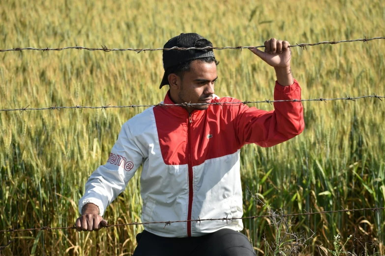 a man sitting on the ground next to a fence