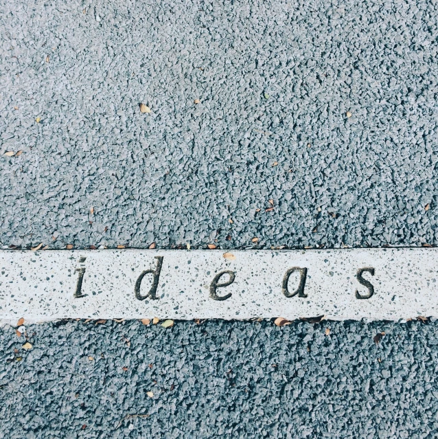 the word idea written on asphalt in front of a stop sign