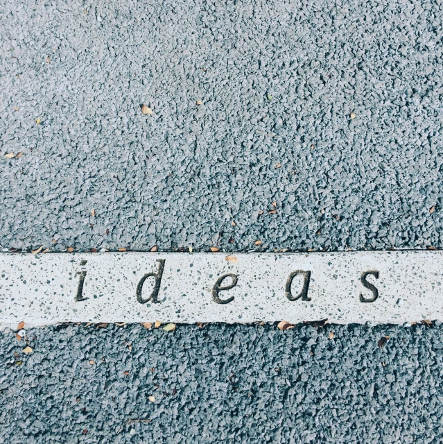 the word idea written on asphalt in front of a stop sign