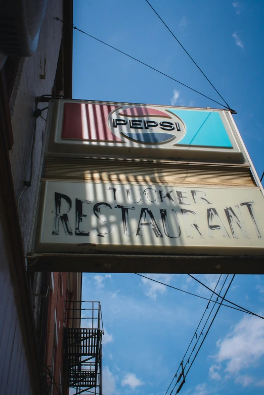 an old restaurant sign outside a building with a sky background