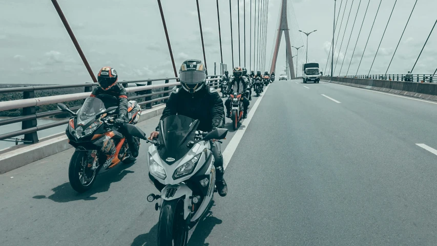 motorcycles are driving on a bridge next to the ocean
