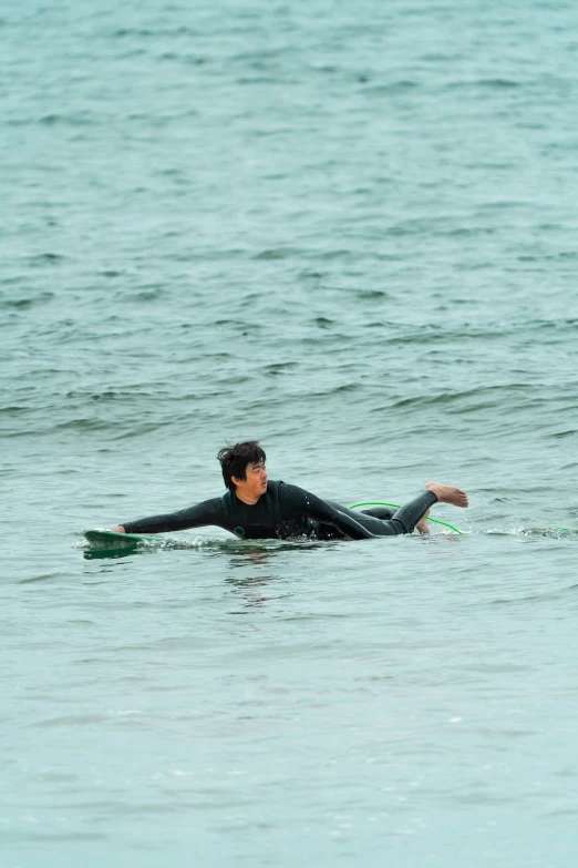 the man in a wet suit is paddling on a surfboard