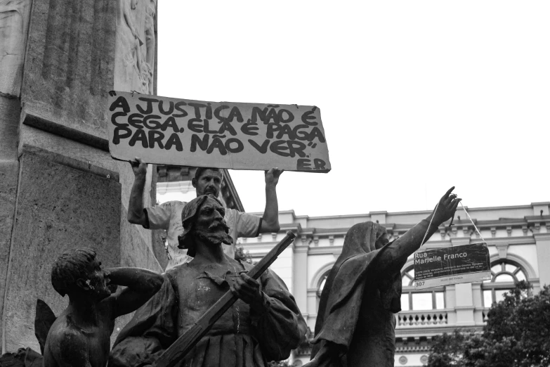 statues hold up a sign while holding a black and white po