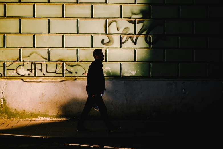 a person walking on a sidewalk near brick wall