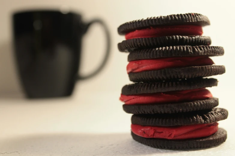 a stack of red and brown cookies in front of a black mug