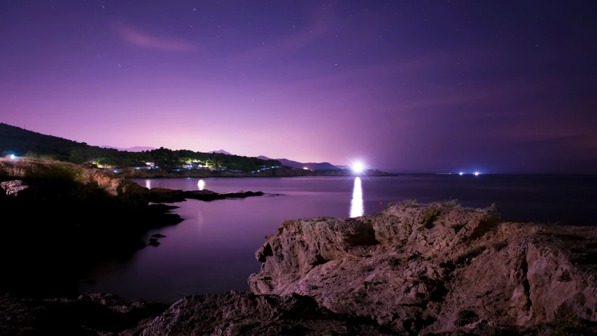 a night time scene with water and a mountain