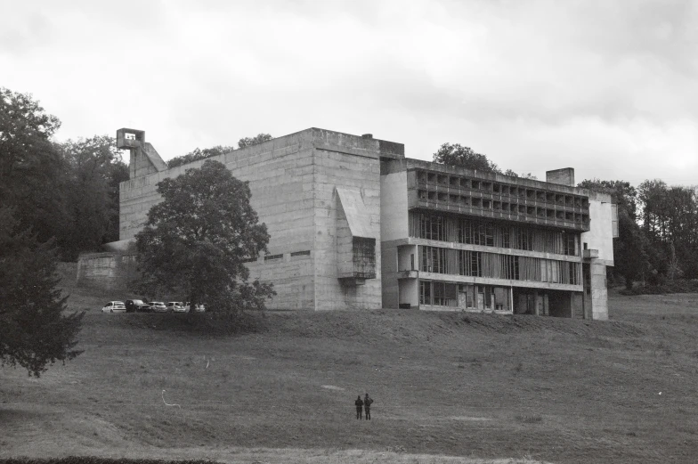 two people standing on grass near trees in front of a building