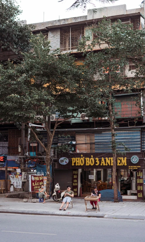 some people sitting on the sidewalk by a building