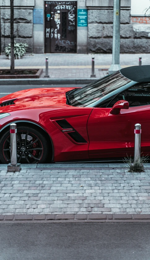 a red car with a black top and hood parked on a sidewalk