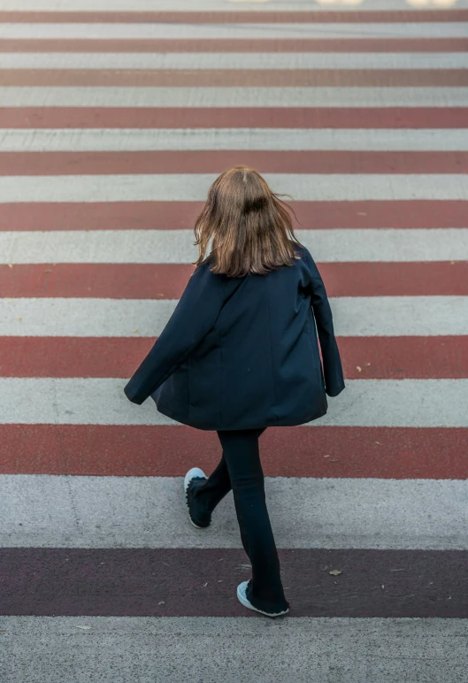 a little girl walking across the street and crossing