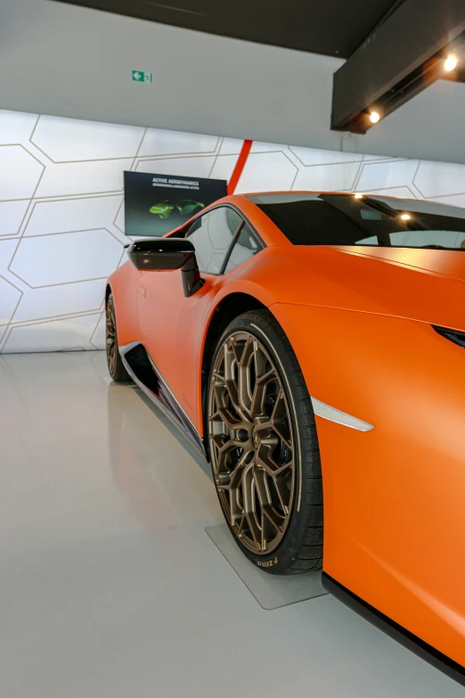 a large orange sports car parked next to a wall