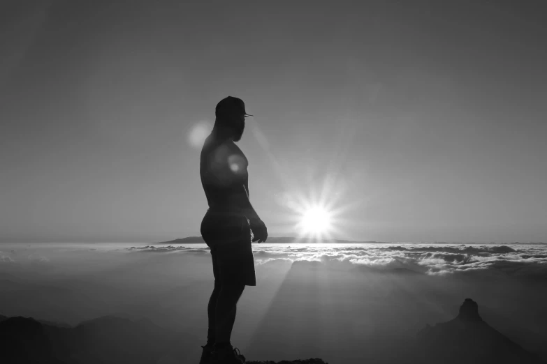 a person stands on a rocky outcropping while the sun shines down