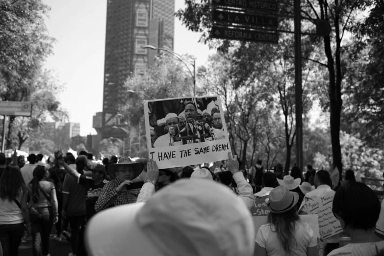 many people are walking on the sidewalk with signs