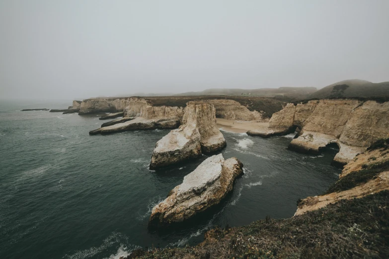 rocks sit out on the shore on a hazy day