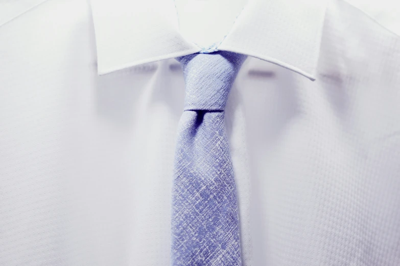 a close up of a blue tie with white dress shirt and a red on down collar