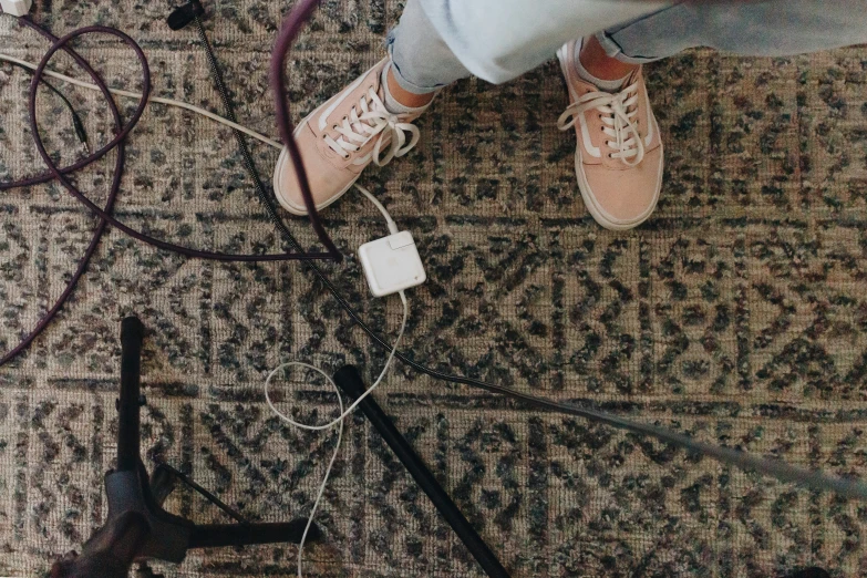 someone's feet standing on an overcast floor next to wires