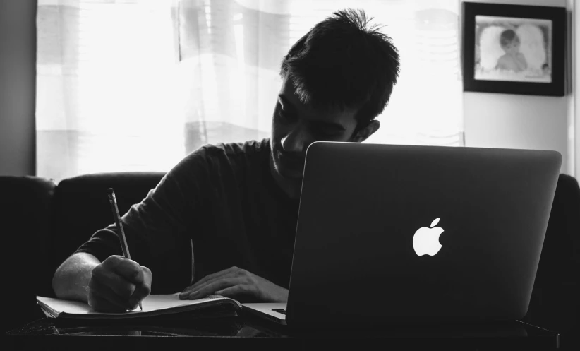 man doing homework with laptop and apple